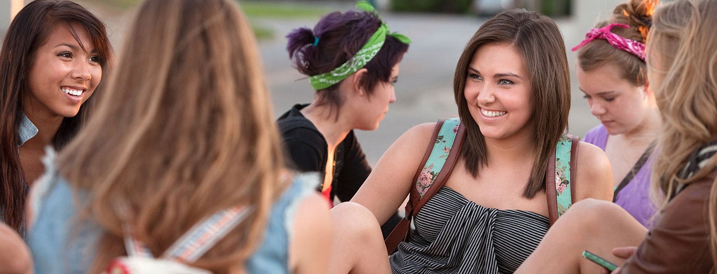 A group of female students hanging out and laughing on campus.