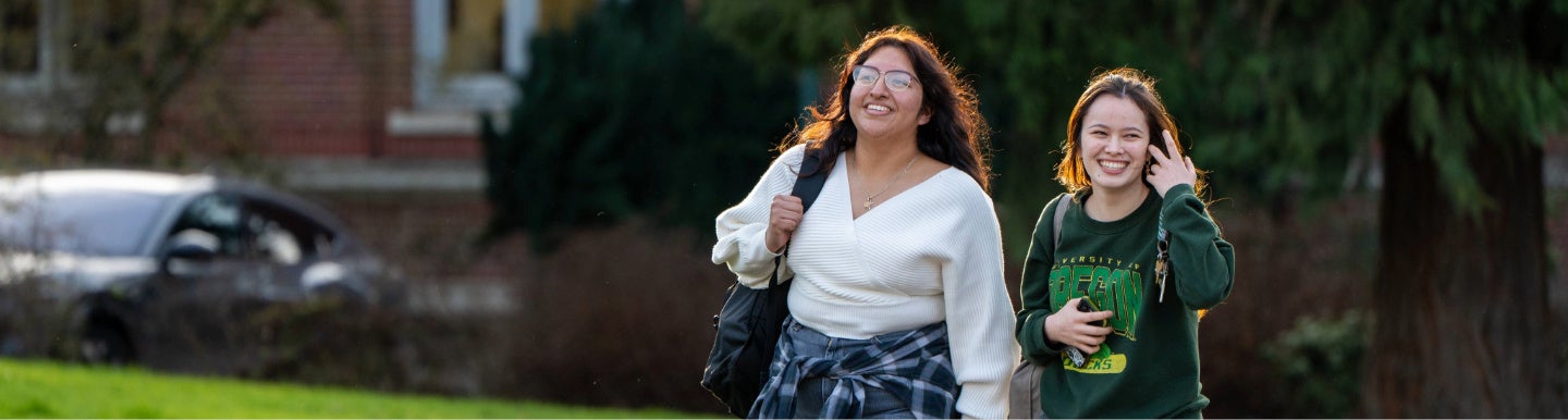 Two students on campus smiling and walking.