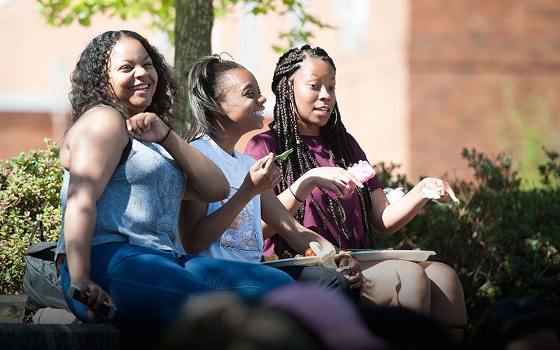 Three students groove to the music at they sit together on the amphitheater steps.